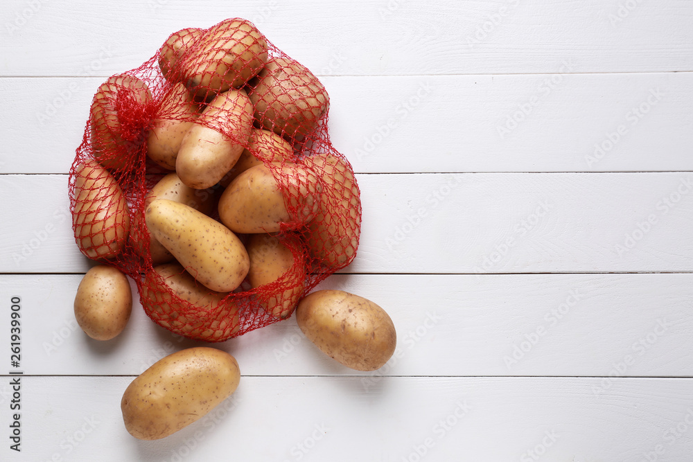 Mash bag with raw potatoes on white table