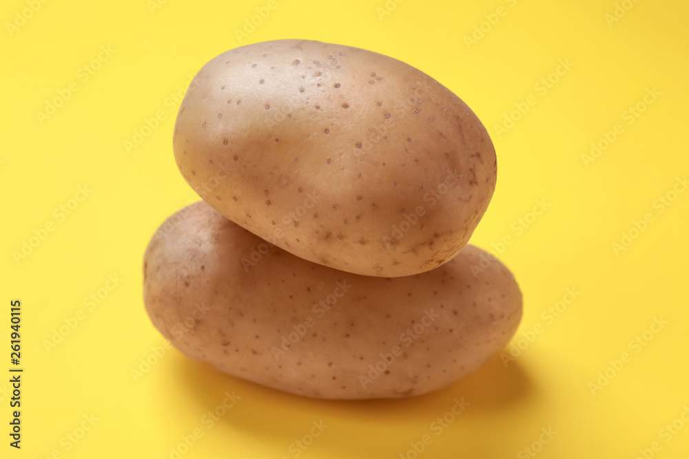 Raw potatoes on color background