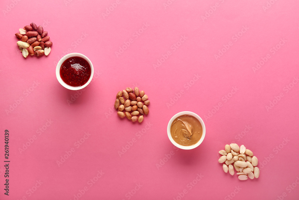 Tasty peanut butter with nuts and jam on color background