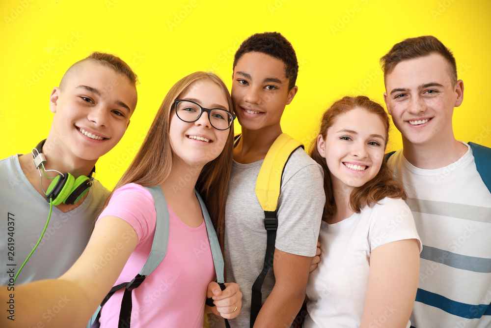 Group of teenagers taking selfie on color background