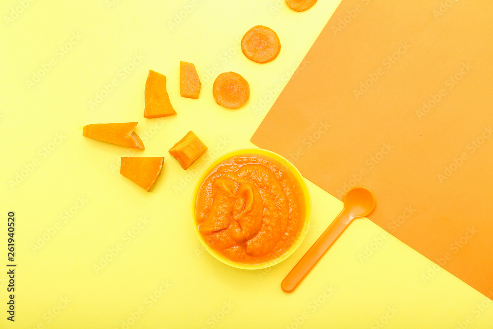 Bowl with healthy baby food on color background