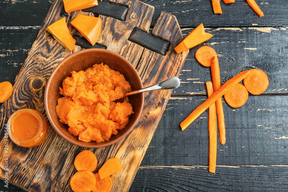 Bowl with healthy baby food on dark wooden background