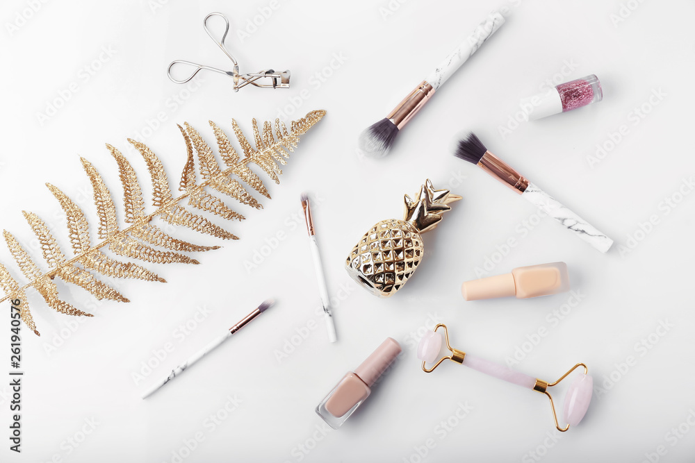 Composition with golden pineapple, tropical leaf, cosmetics and accessories on white background