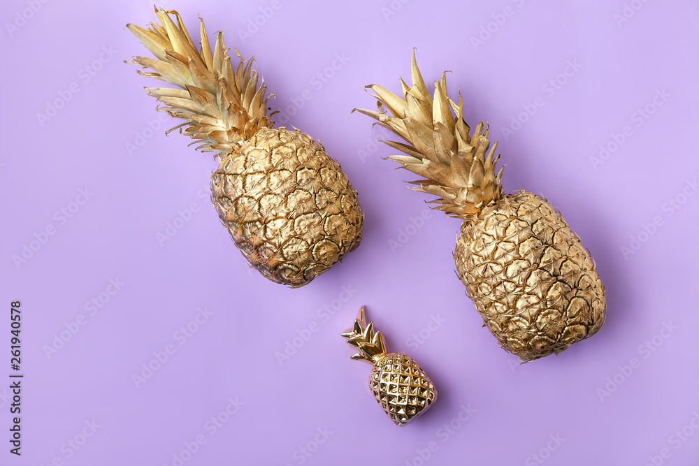 Golden pineapples on color background