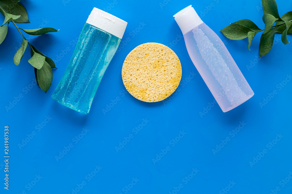 skin care cosmetics with facial tonic, mycelial water and sponge on blue background top view mockup