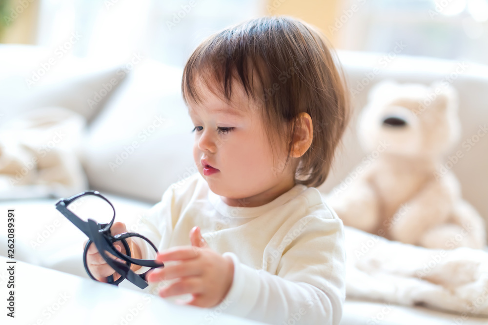 One year old toddler boy with eyeglasses in a living room