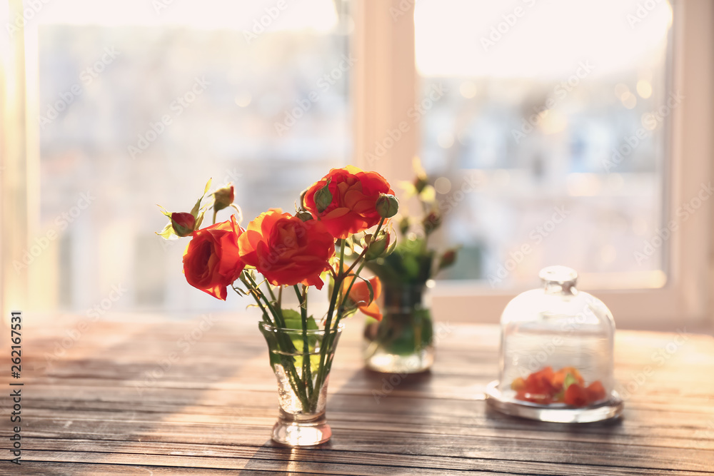 Beautiful flowers on wooden table near window