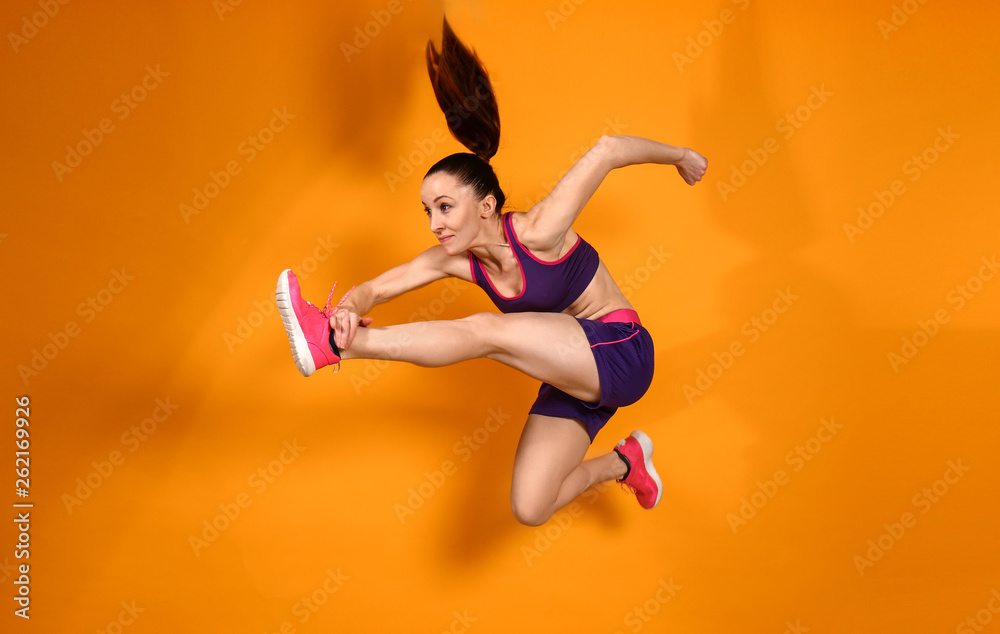 Sporty jumping woman on color background