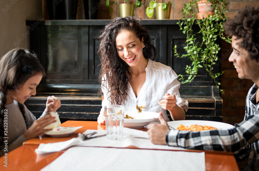 Happy african american family eating lunch together at restaurant and having fun