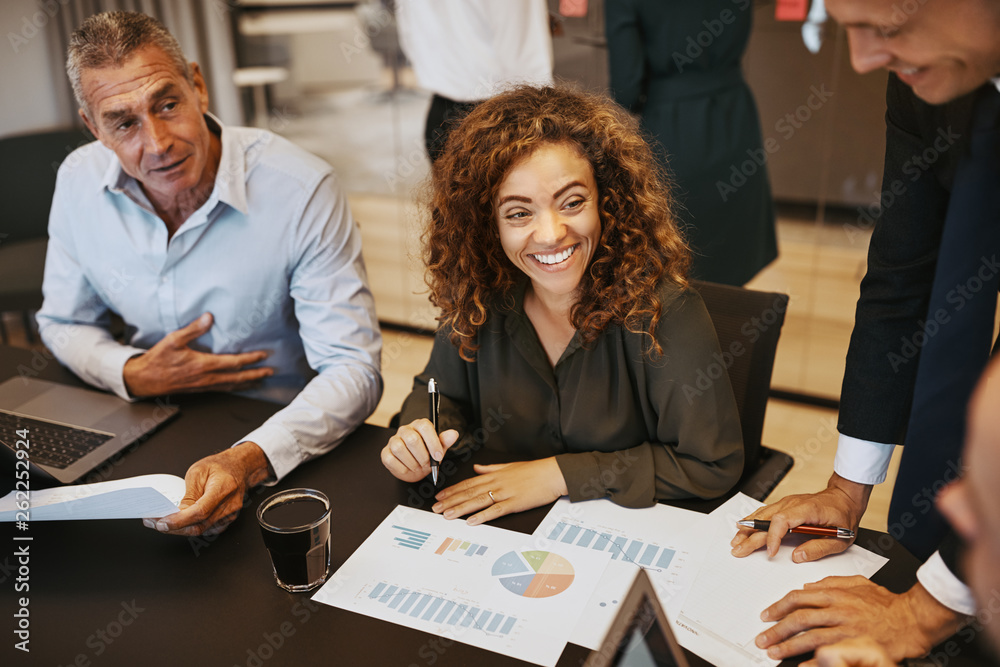 Smiling young businesswoman discussing graphs with office collea