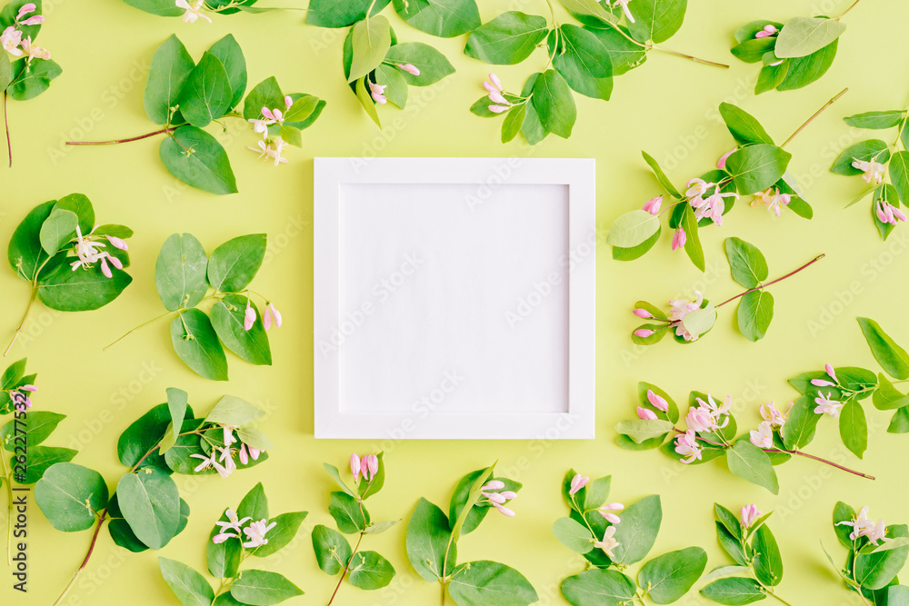 Mockup square white frame with branches and green leaves on a green background