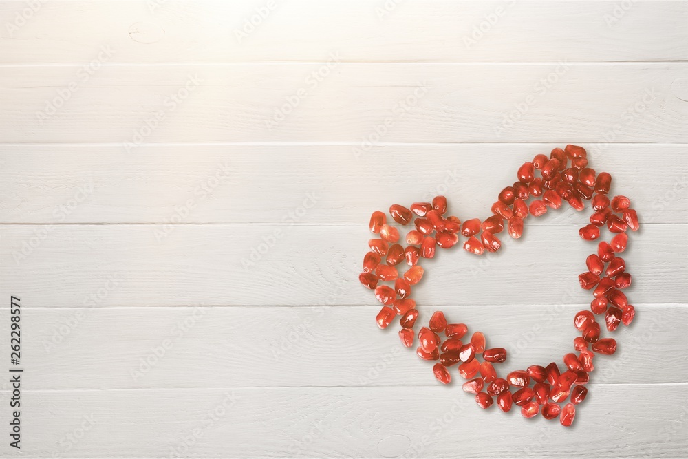 Pomegranate seeds in shape of heart on white background