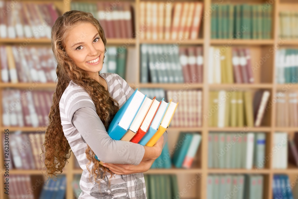 Beautiful female student in library with notebook