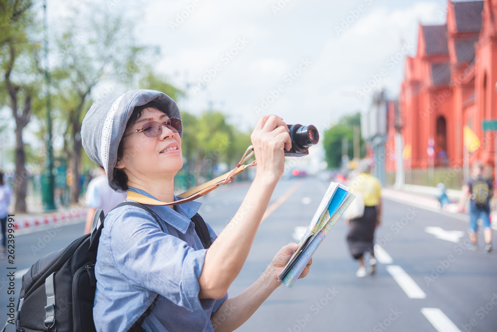 资深亚洲女游客在泰国曼谷旅游时用相机拍照。