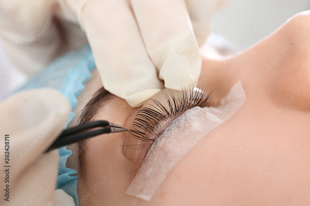 Young woman undergoing procedure of eyelashes lamination in beauty salon, closeup