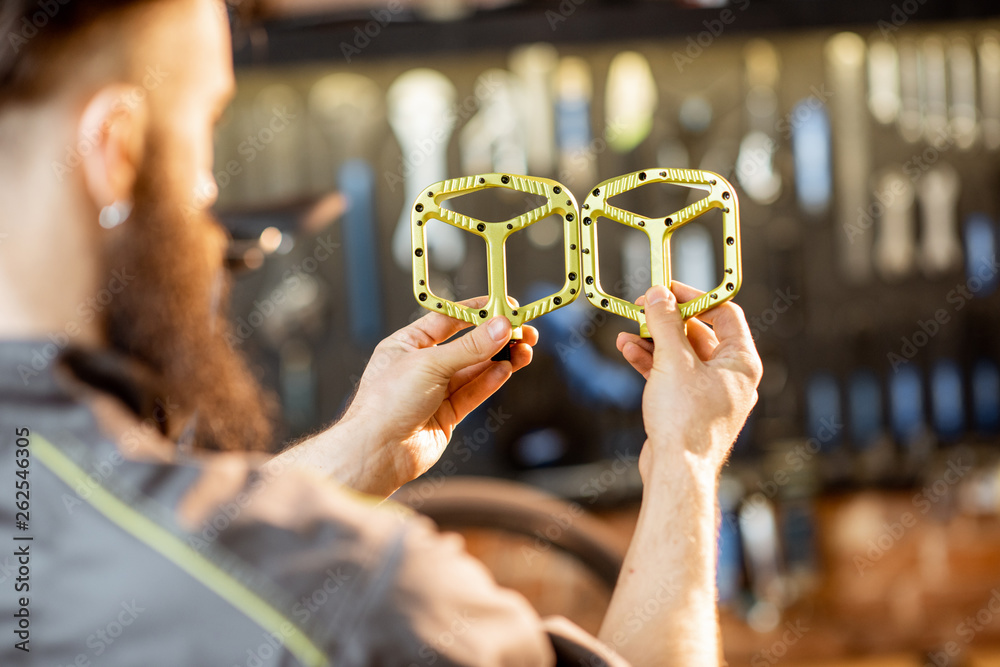 Repairman holding bicycle pedals before installing them at the bicycle workshop