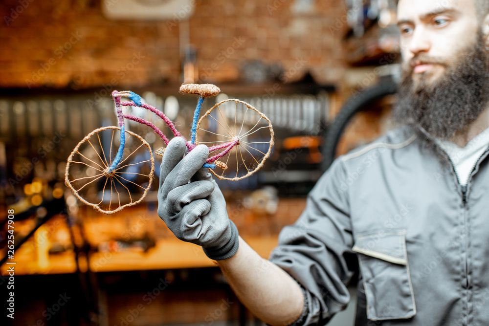 Repairman holding a small toy bicycle at the bicycle workshop