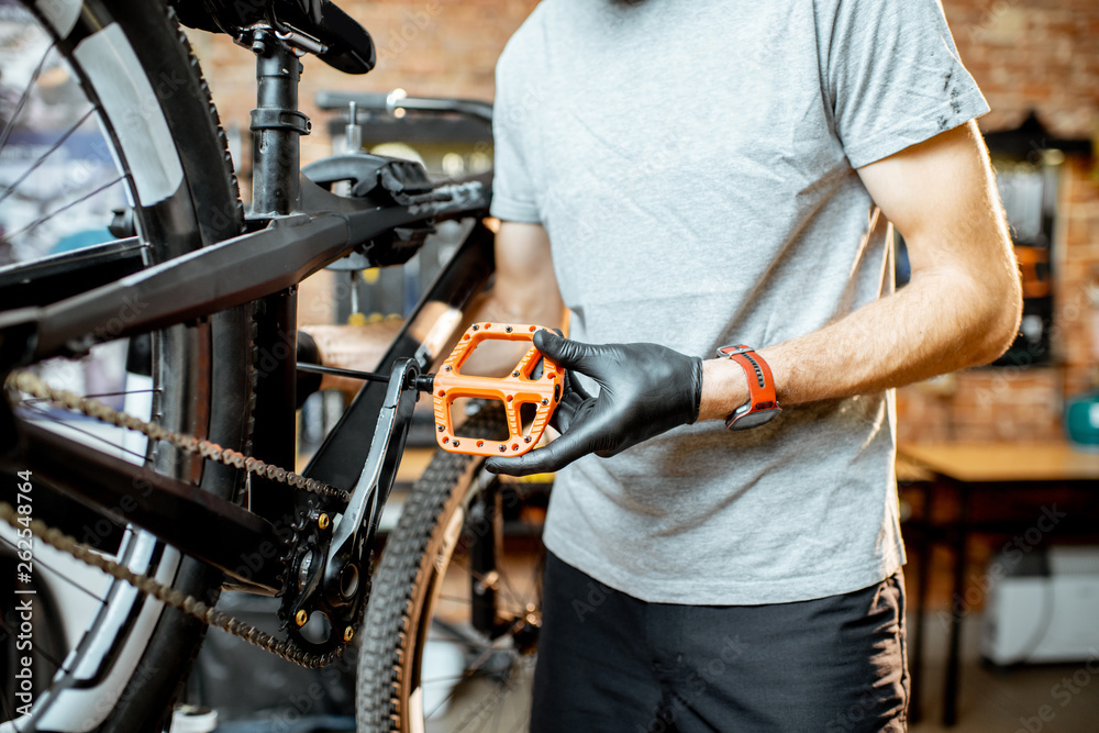 Repairman installing new pedals on a mountain bicycle at the workshop