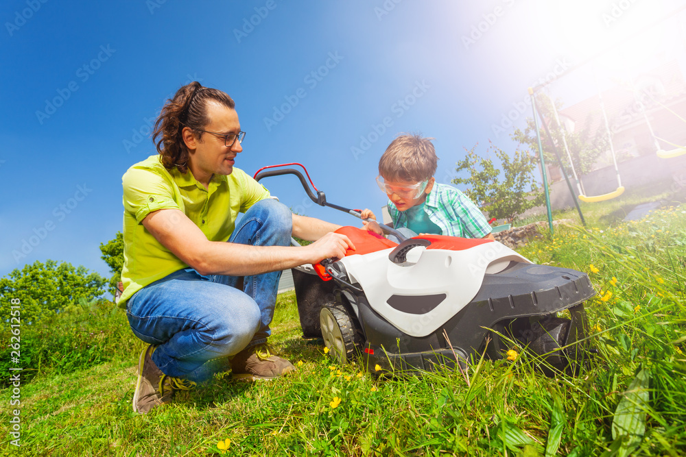 Father and son cleaning lawnmower after work