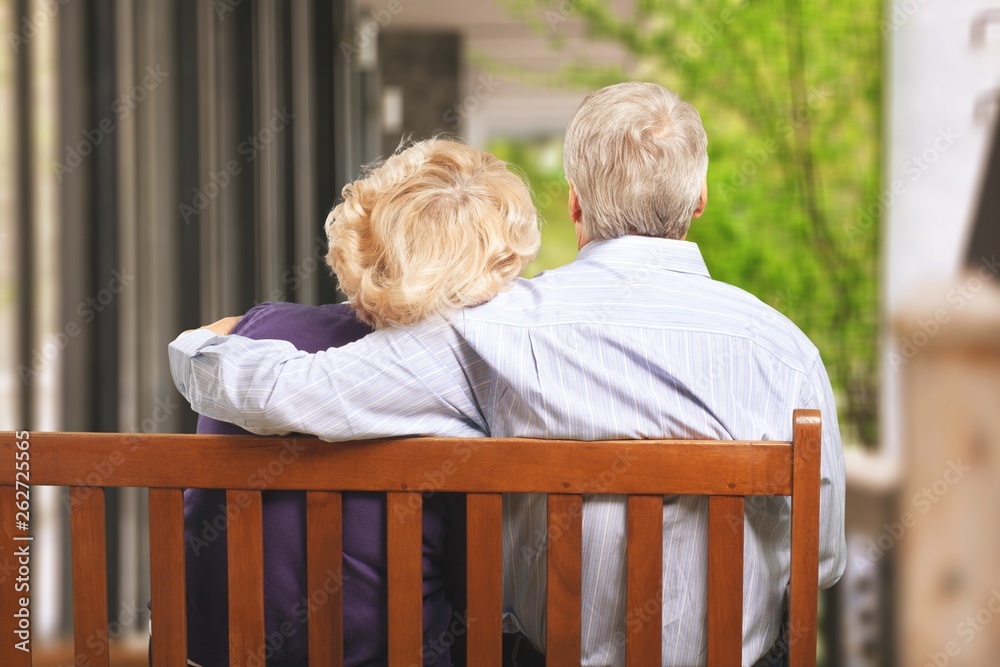 Portrait of happy senior couple in green blurred park background, bokeh