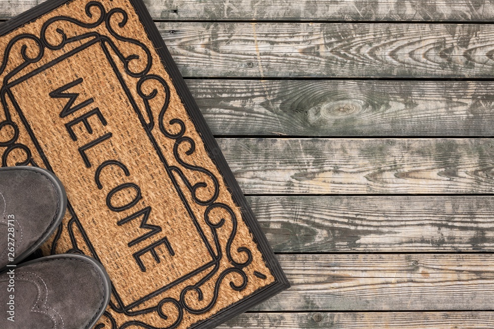 Welcome cleaning foot carpet with shoes and shoe print on it.