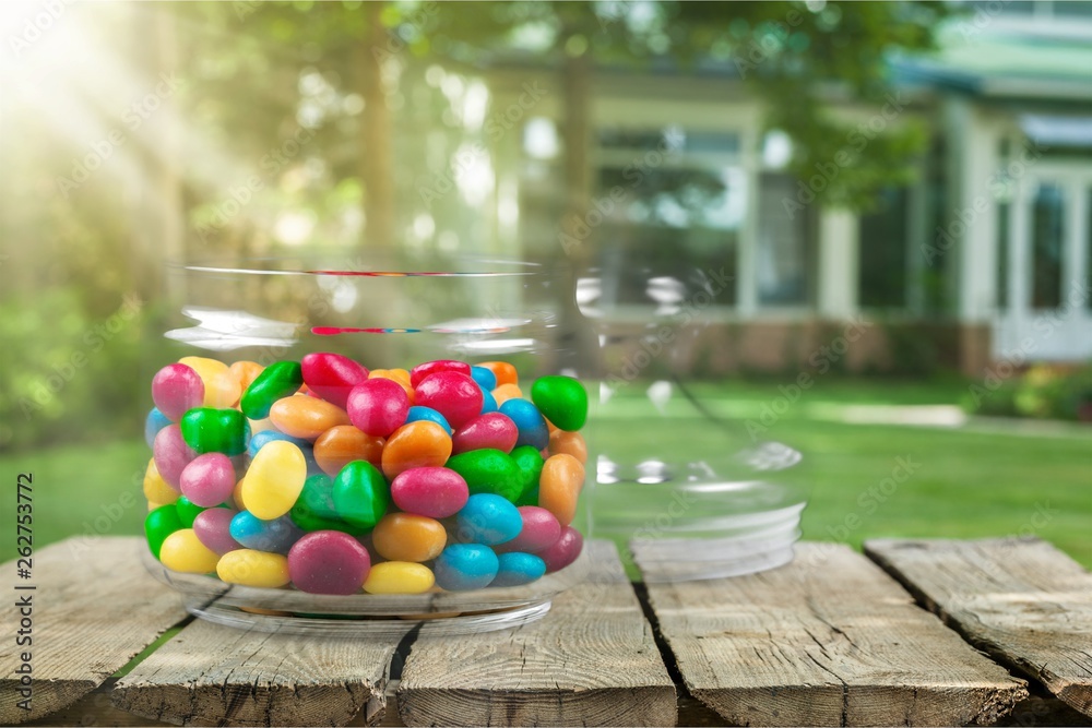 Transparent glass jar with colorful chocolate candies on table