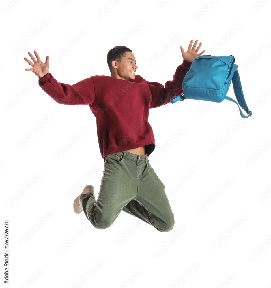 Portrait of jumping African-American teenage boy with backpack on white background