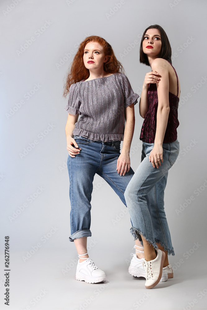 Portrait of fashionable young women on grey background