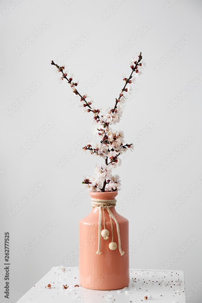 Vase with beautiful blossoming branches on light background