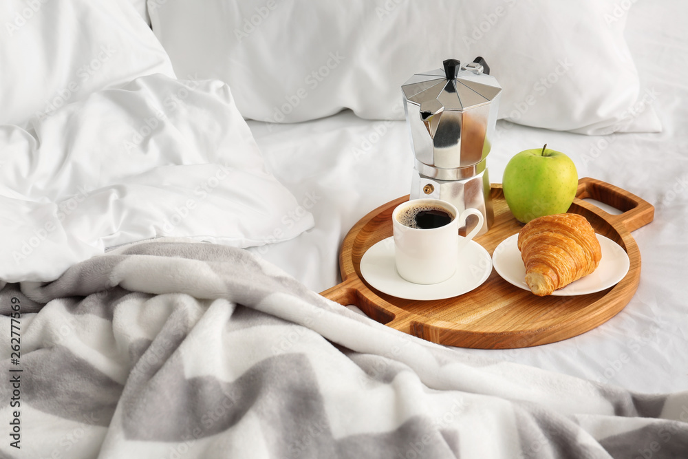 Tray with tasty breakfast on bed