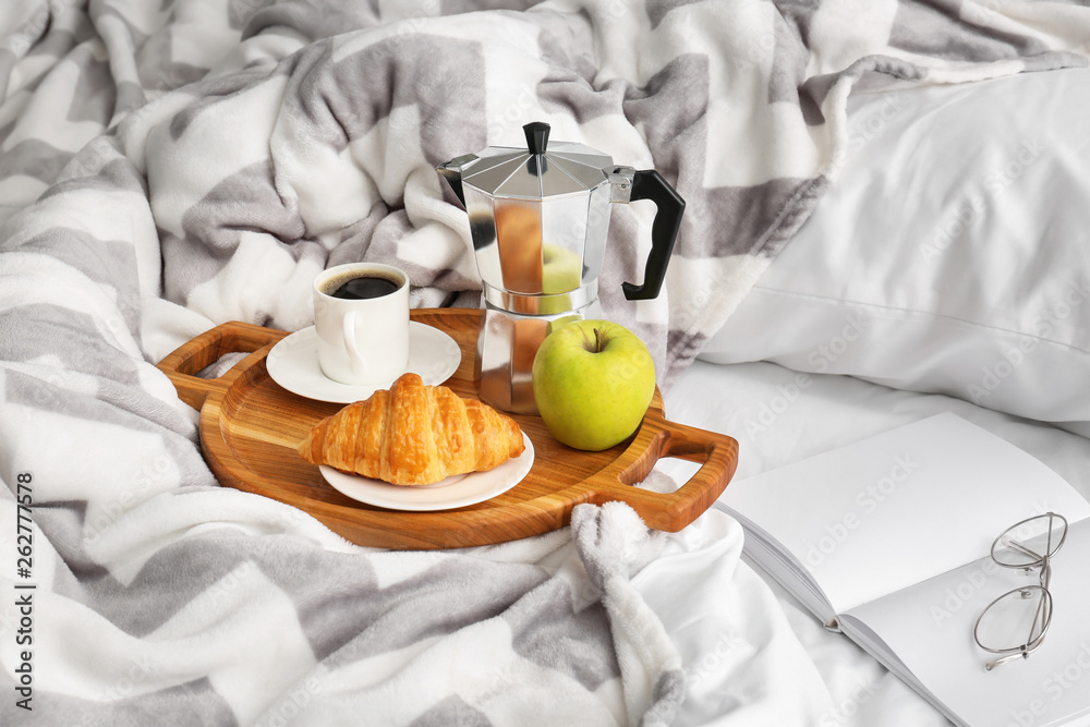 Tray with tasty breakfast on bed