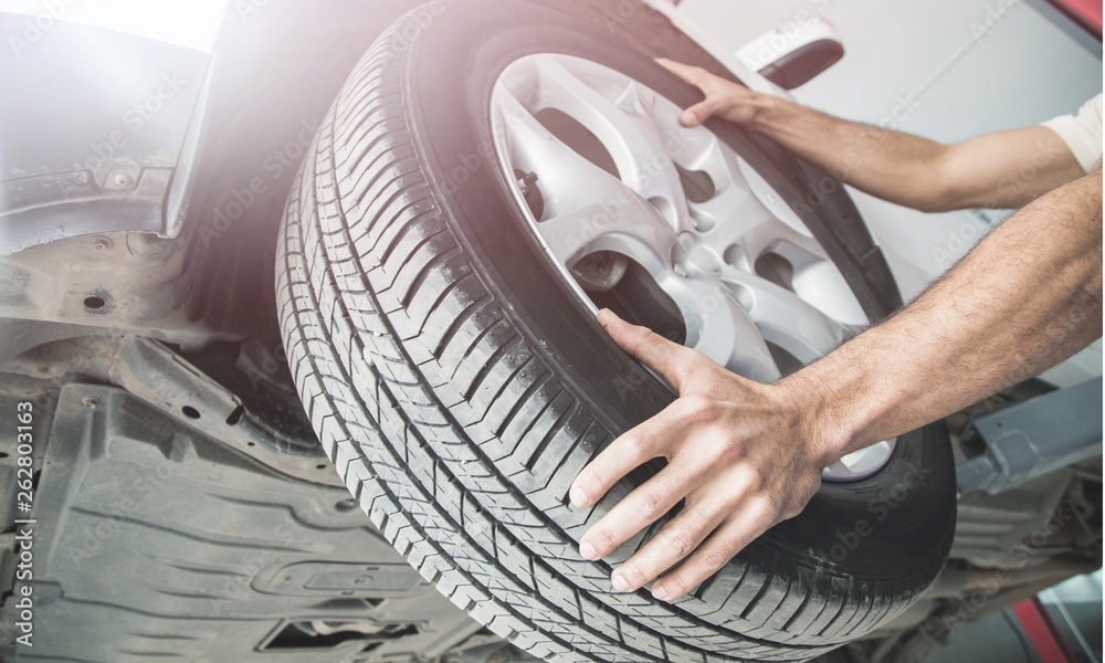 Male hands with Automobile tires on background