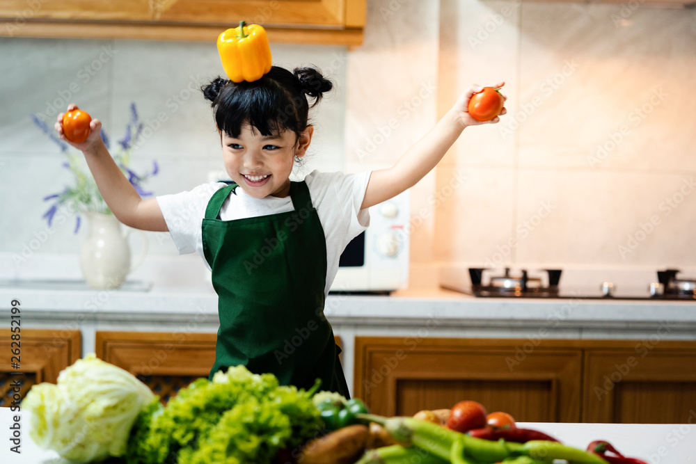 Asian kid in the kitchen at home. Kid enjoy cooking the healthy food with variety of vegetable.