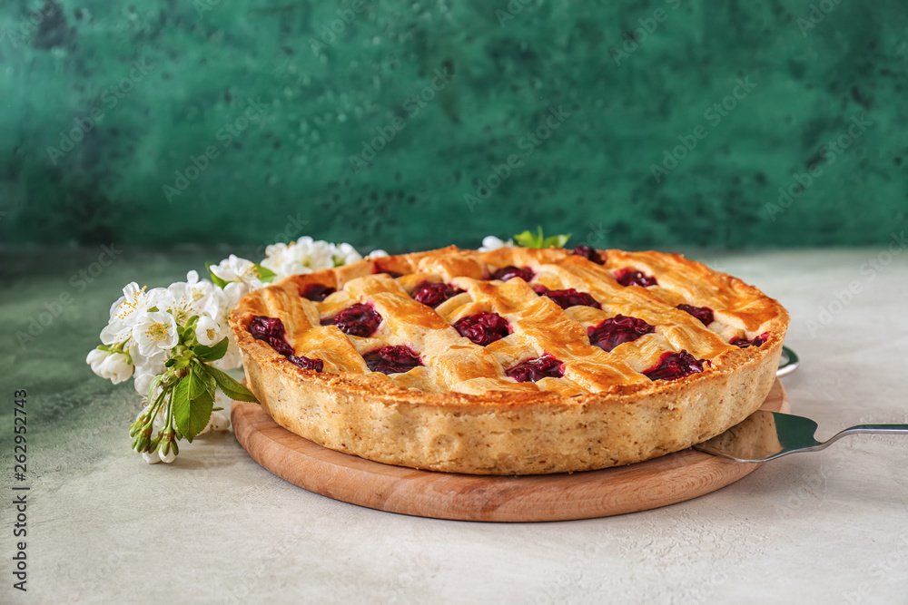 Tasty cherry pie and flowers on table