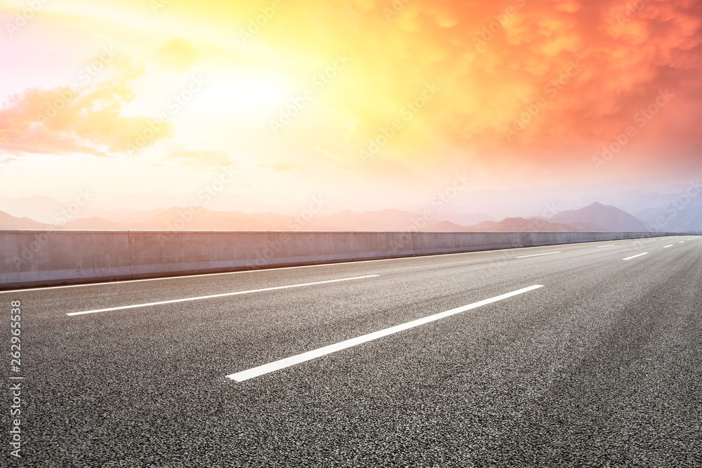 Empty asphalt road and mountains with beautiful clouds at sunset