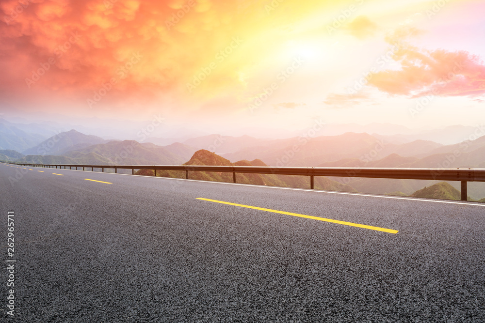 Empty asphalt road and mountains with beautiful clouds at sunset