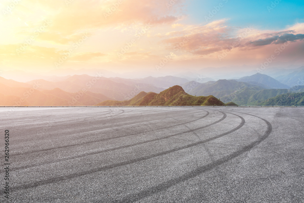 Asphalt race track ground and mountain with sunset clouds