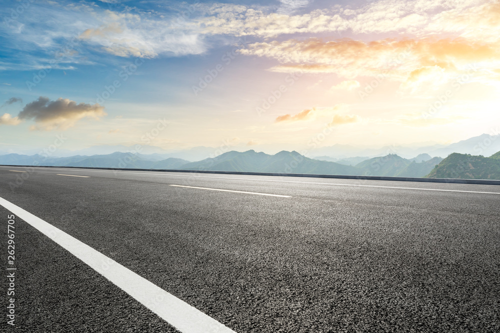 Empty asphalt road and mountains with beautiful clouds at sunset