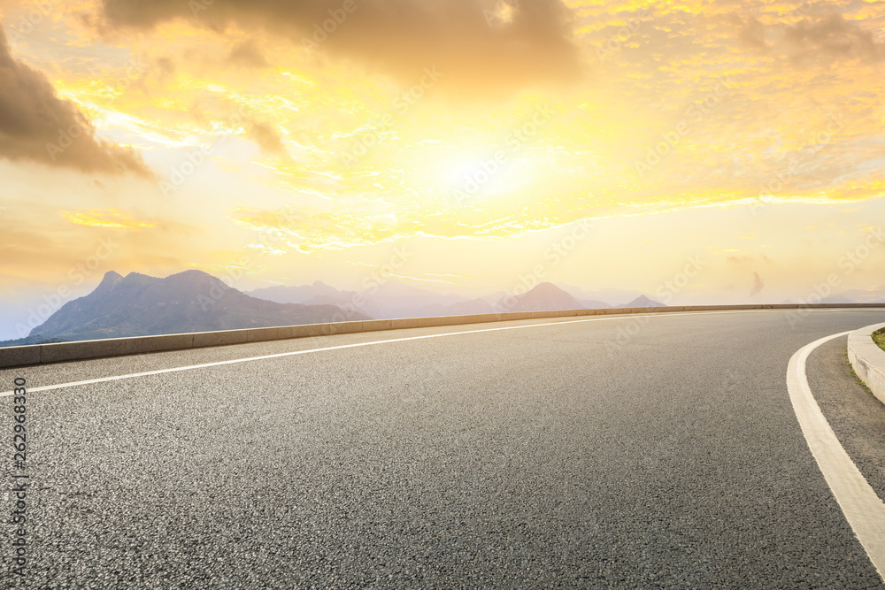 Empty asphalt road and mountains with beautiful clouds at sunset