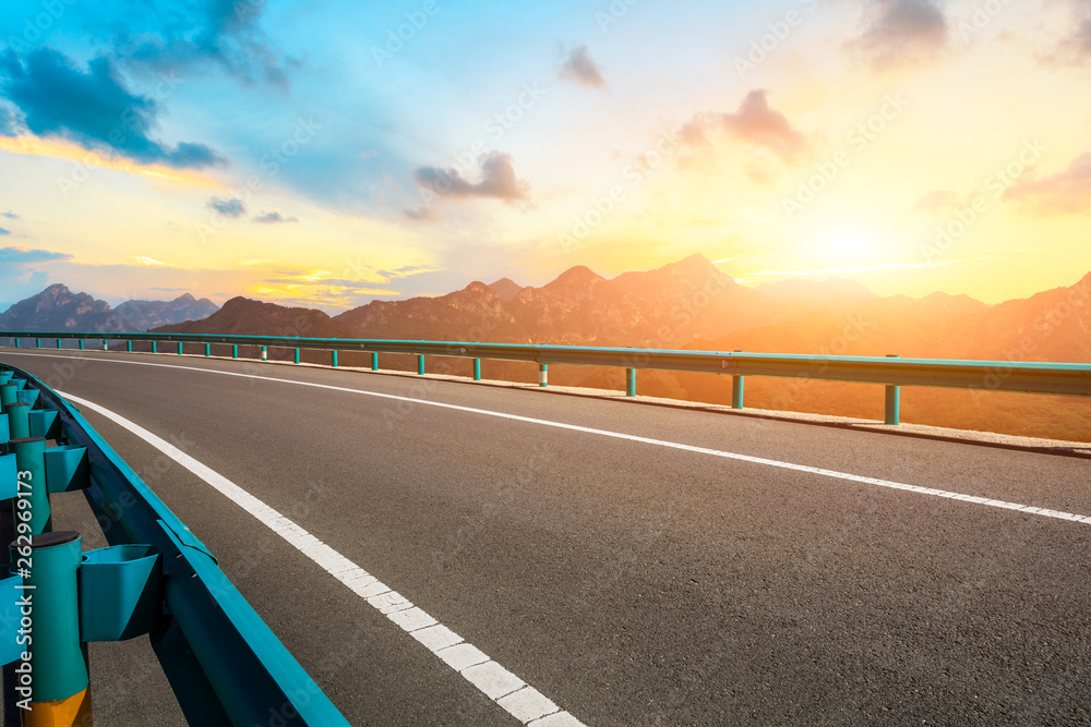 Empty asphalt road and mountains with beautiful clouds at sunset