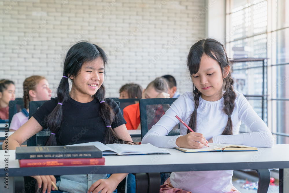 two little girls writing and talking