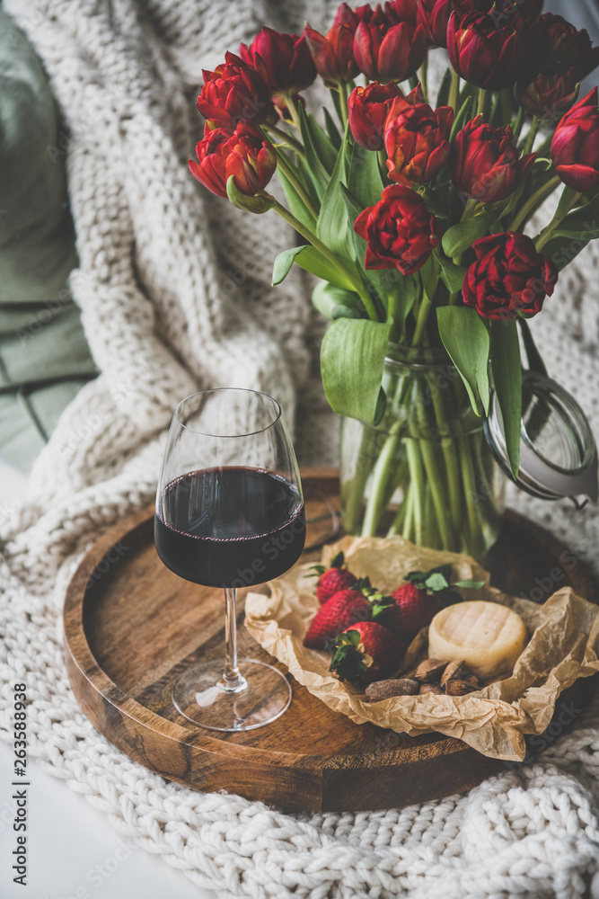 Wine snack set with flowers. Glass of red wine, cheese, roasted almonds, strawberries and bouquet of