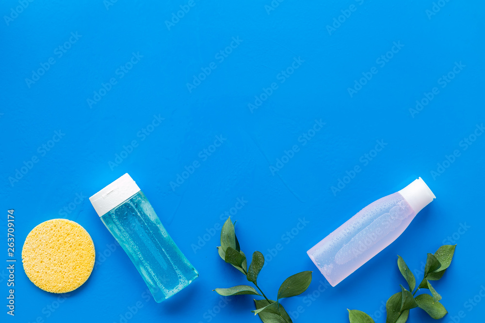 skin care cosmetics with facial tonic, mycelial water and sponge on blue background top view mockup