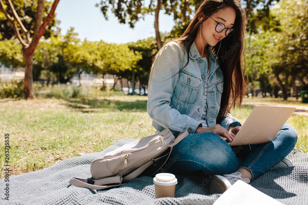 Student using laptop sitting in college campus