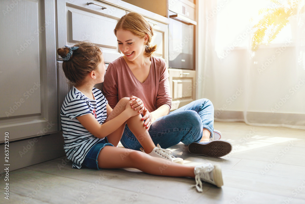 family mother and child daughter hugging in kitchen on floor