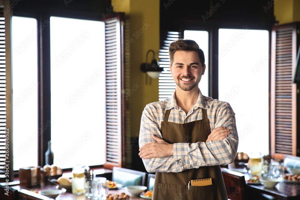 Young male waiter in restaurant