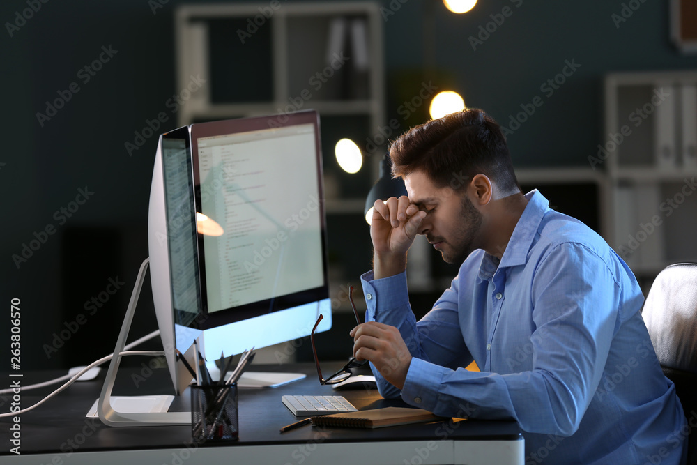 Tired male programmer working in office