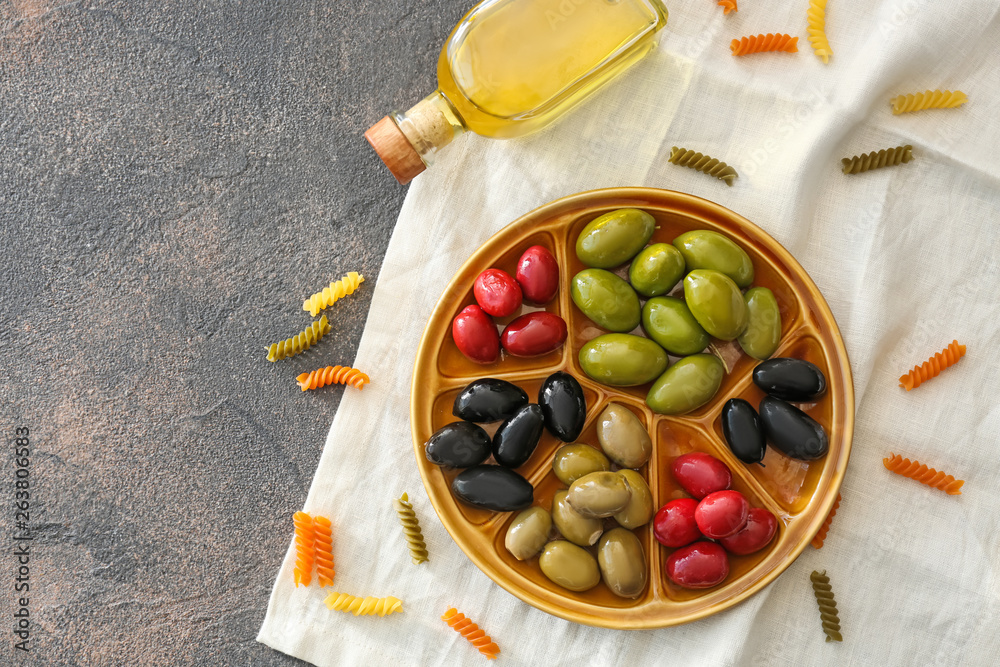 Plate with tasty olives on grey table