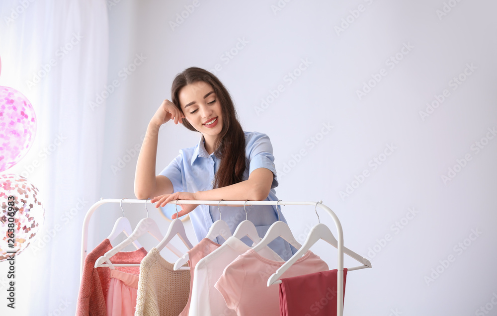 Young woman standing near clothes rack in dressing room