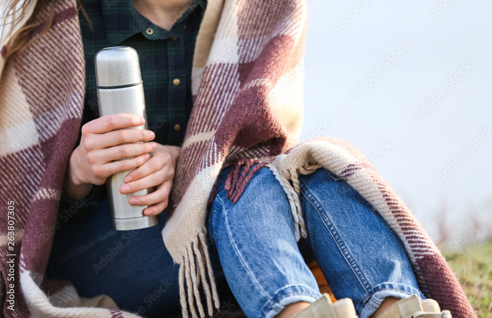 拿着保温瓶的女人在户外休息